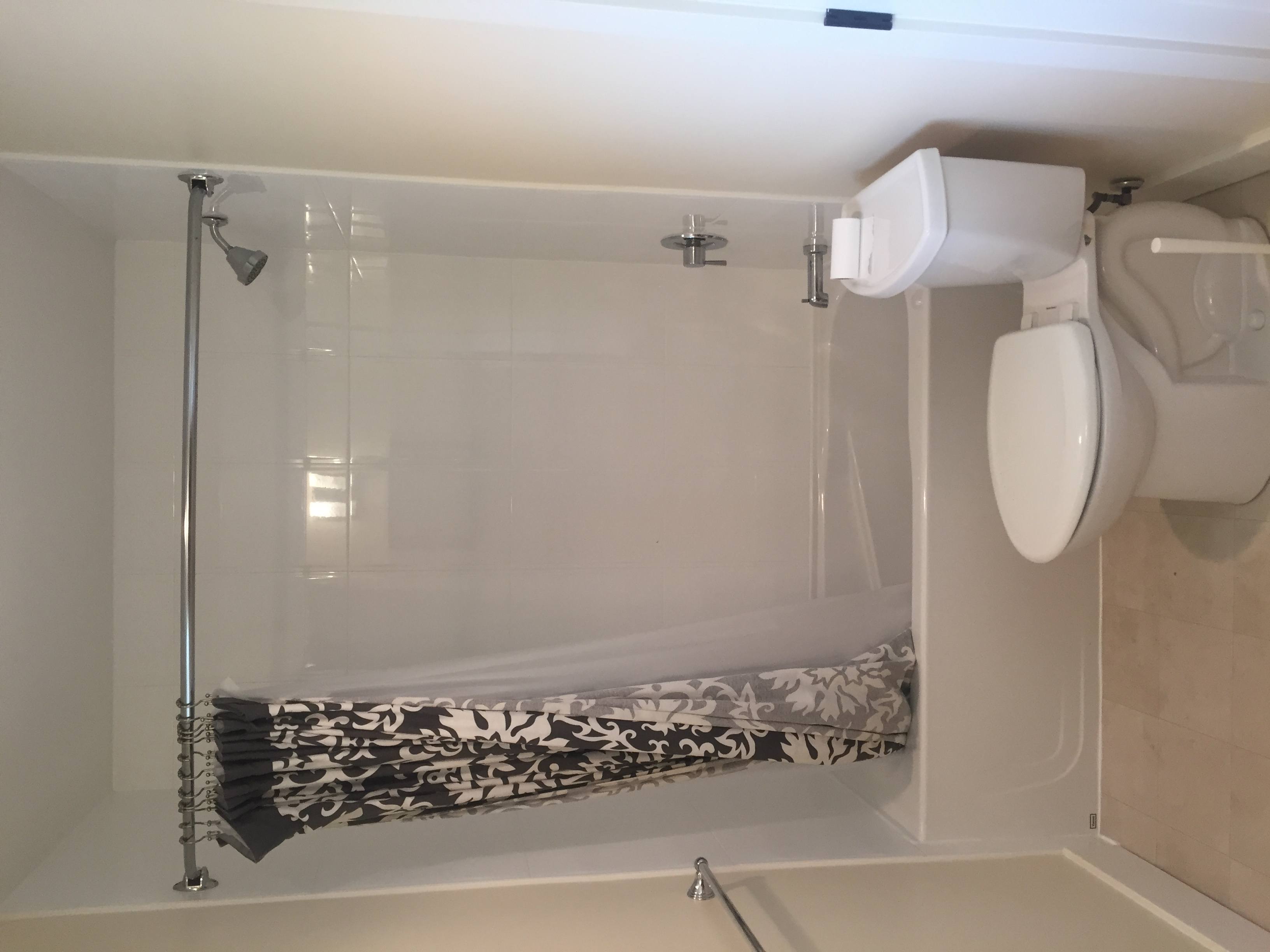 A white toilet is installed in a small bathroom with a glass shower door.